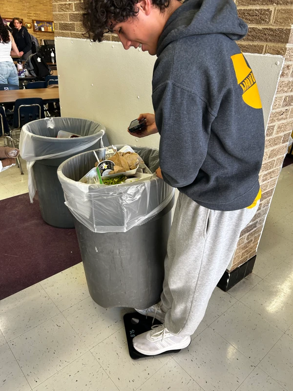 Jackson leaning over a trash can, performing a trash audit