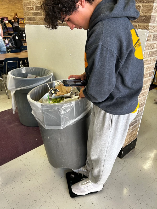Jackson leaning over a trash can, performing a trash audit