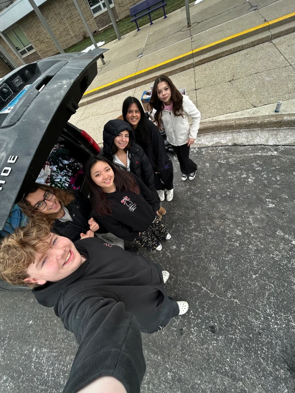 Students standing next to a full trunk of blankets for the Verdance for Veterans initiative