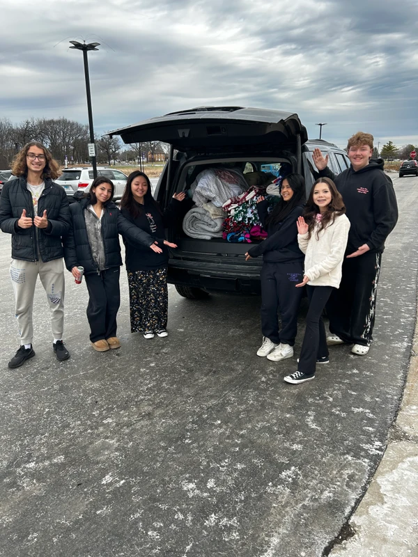 Volunteer students standing next to a full trunk of blankets for the Verdance for Veterans initiative